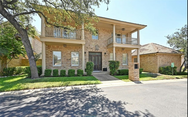 view of front of property with a balcony, a front lawn, and central AC unit