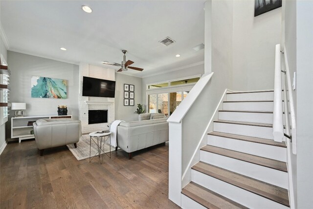 interior space with hardwood / wood-style flooring, ornamental molding, ceiling fan, and a brick fireplace