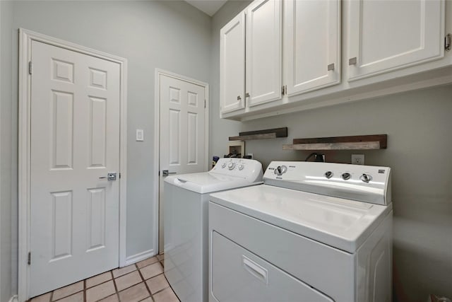 laundry area with separate washer and dryer, light tile patterned floors, and cabinets