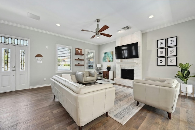 living room featuring ceiling fan, dark hardwood / wood-style floors, a fireplace, and crown molding