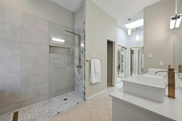 bathroom featuring a skylight, vanity, tile patterned flooring, and tiled shower