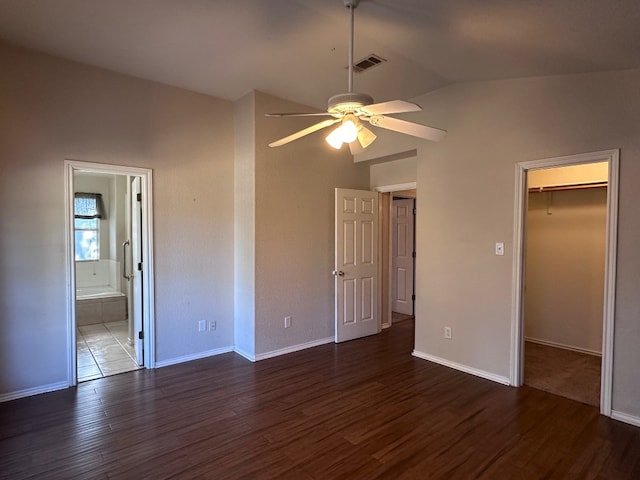 unfurnished bedroom with a closet, dark wood-type flooring, ensuite bath, a spacious closet, and ceiling fan