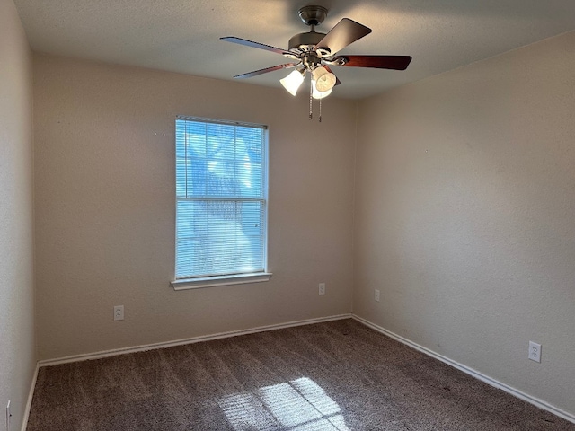 spare room featuring dark carpet and ceiling fan