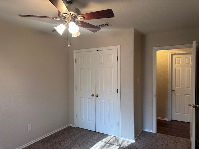 unfurnished bedroom with dark colored carpet, ceiling fan, and a closet