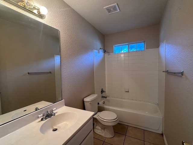 full bathroom featuring vanity, tiled shower / bath combo, a textured ceiling, tile patterned floors, and toilet