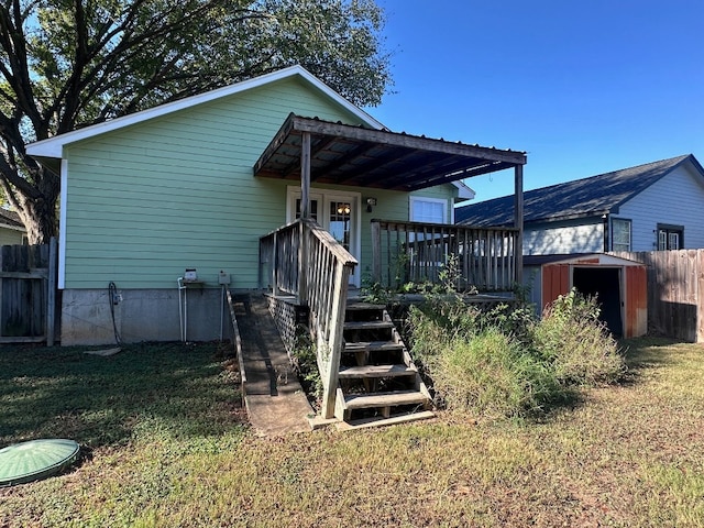 back of house with a shed, a yard, and a wooden deck