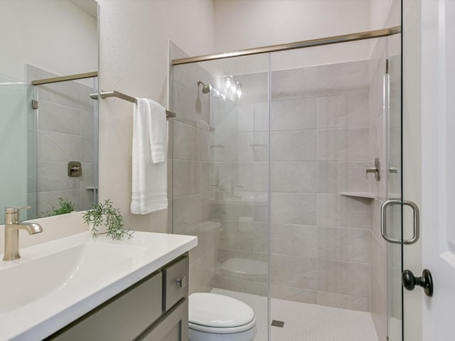 bathroom with vanity, a shower with door, and toilet