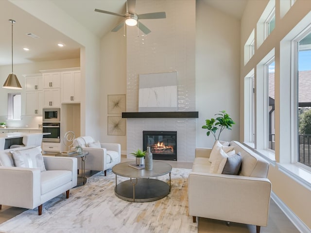 living room with ceiling fan, high vaulted ceiling, and a large fireplace