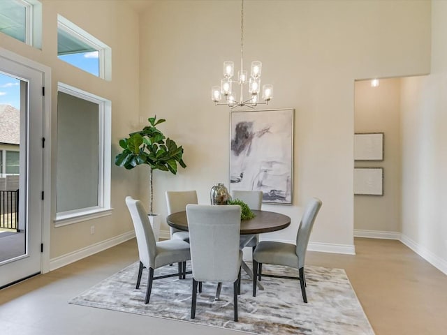 dining space featuring a chandelier, a towering ceiling, and baseboards