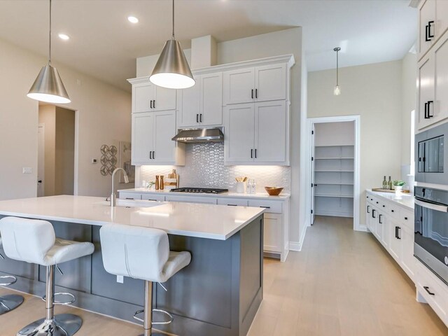 kitchen featuring hanging light fixtures, decorative backsplash, white cabinets, appliances with stainless steel finishes, and sink