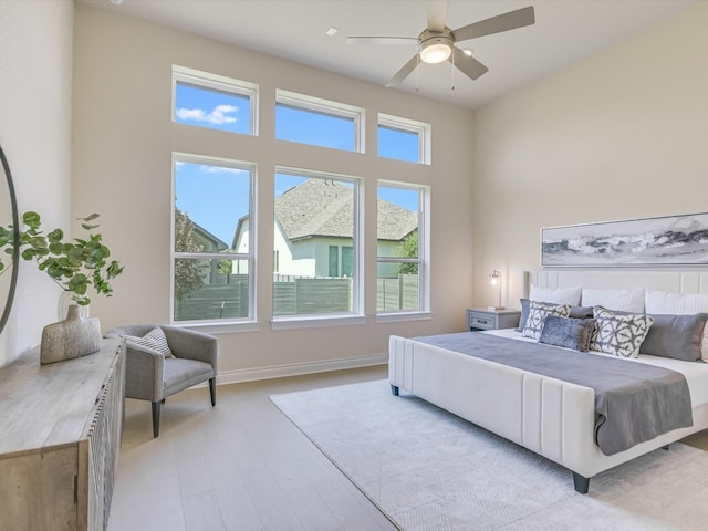 bedroom featuring ceiling fan, multiple windows, and light hardwood / wood-style floors