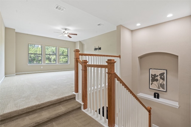 stairs featuring ceiling fan and carpet