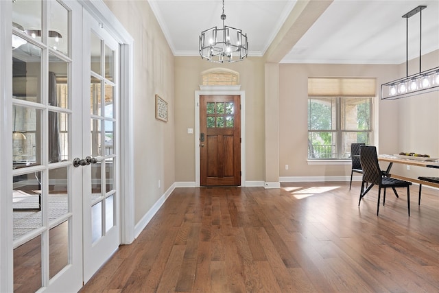 foyer with a notable chandelier, french doors, crown molding, and hardwood / wood-style floors