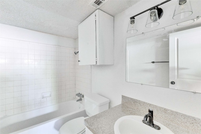 full bathroom with tiled shower / bath combo, a textured ceiling, vanity, and toilet