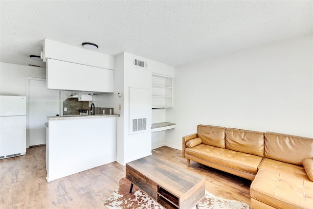 living room with light hardwood / wood-style flooring, sink, and a textured ceiling