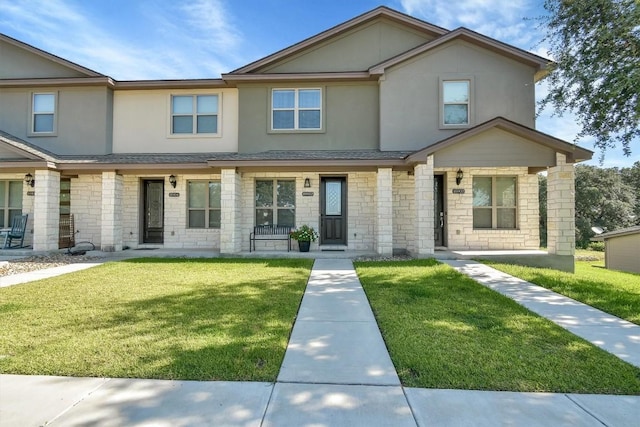 view of property featuring stone siding, roof with shingles, stucco siding, and a front yard