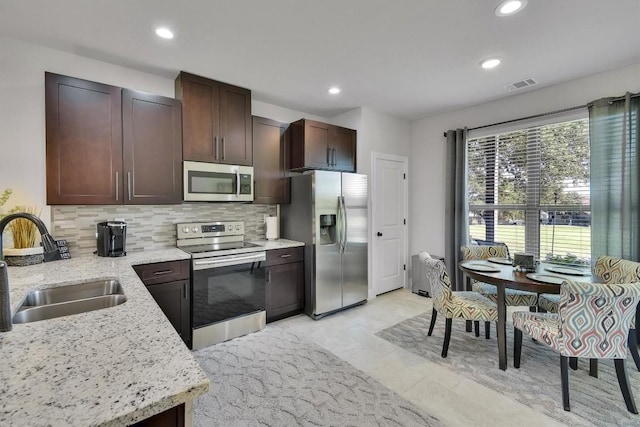 kitchen featuring light stone counters, visible vents, backsplash, appliances with stainless steel finishes, and a sink