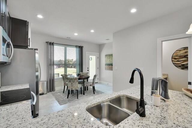 kitchen featuring sink, light stone counters, light tile patterned flooring, and stove