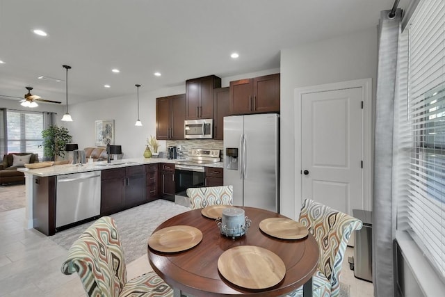 kitchen with pendant lighting, tasteful backsplash, appliances with stainless steel finishes, open floor plan, and a sink