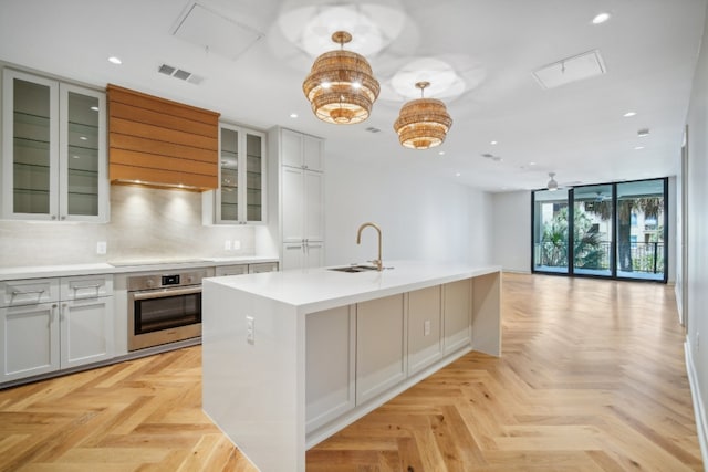 kitchen featuring pendant lighting, stainless steel oven, and light parquet floors