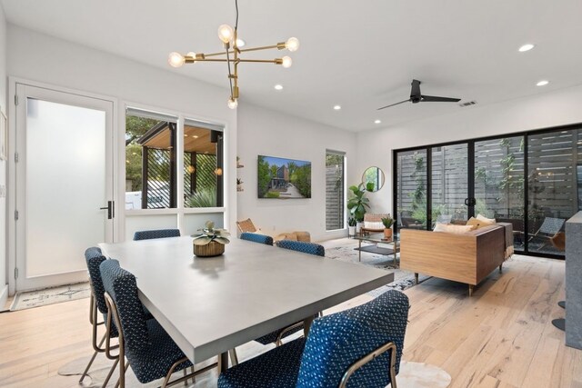 dining space featuring ceiling fan with notable chandelier and light hardwood / wood-style floors