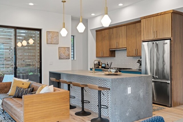 kitchen with backsplash, light wood-type flooring, high end refrigerator, and a wealth of natural light