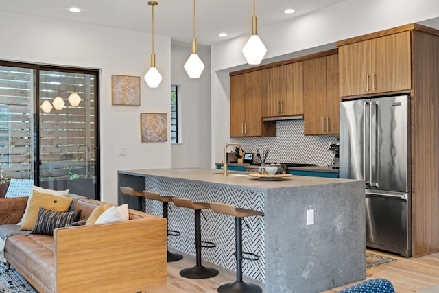 2118 Glendale Pl Unit 1, Austin, TX 78704 - kitchen featuring high end fridge, tasteful backsplash, a kitchen breakfast bar, light wood-style floors, and decorative light fixtures