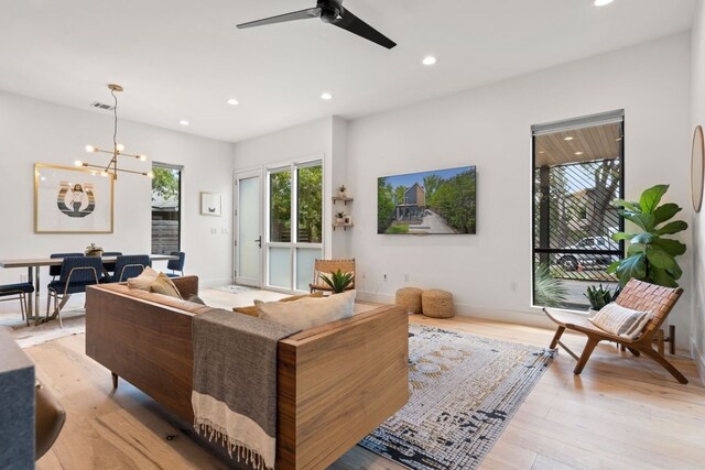 living room featuring ceiling fan with notable chandelier and light hardwood / wood-style floors