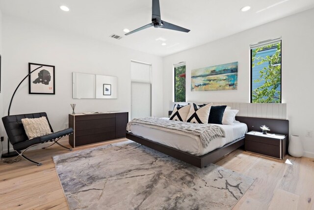 bedroom featuring light wood-type flooring, ceiling fan, and multiple windows