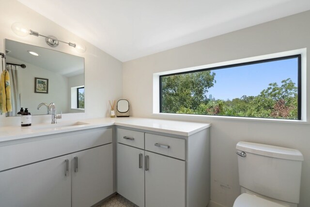 bathroom with toilet, tile patterned floors, vanity, and vaulted ceiling