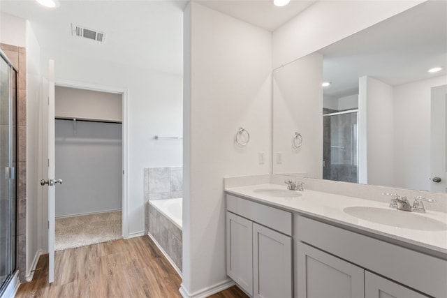 bathroom with hardwood / wood-style floors, vanity, and shower with separate bathtub