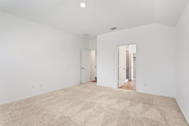 unfurnished bedroom with a walk in closet, light colored carpet, and vaulted ceiling