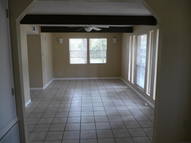 tiled empty room with a textured ceiling, beam ceiling, and ceiling fan