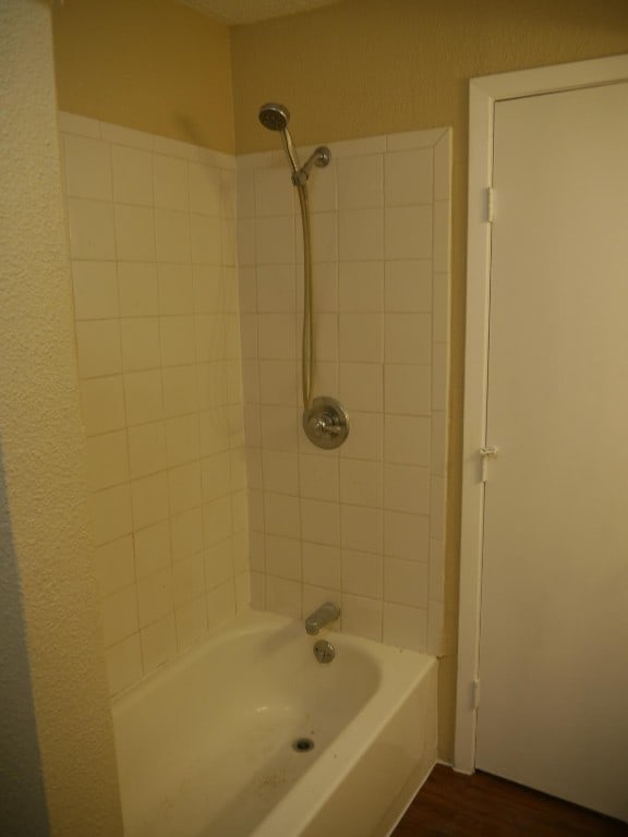 bathroom with tiled shower / bath and wood-type flooring