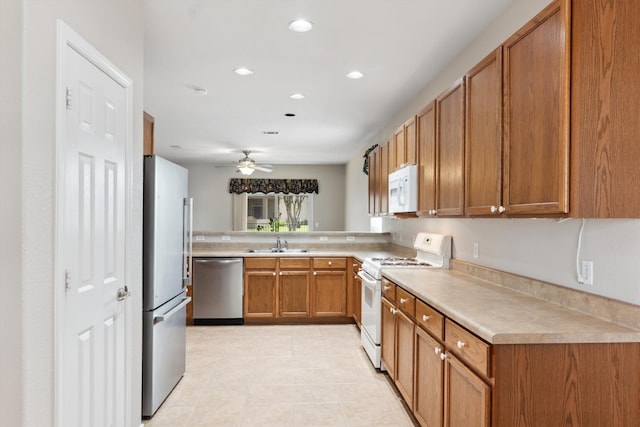 kitchen featuring ceiling fan, kitchen peninsula, light tile patterned floors, stainless steel appliances, and sink