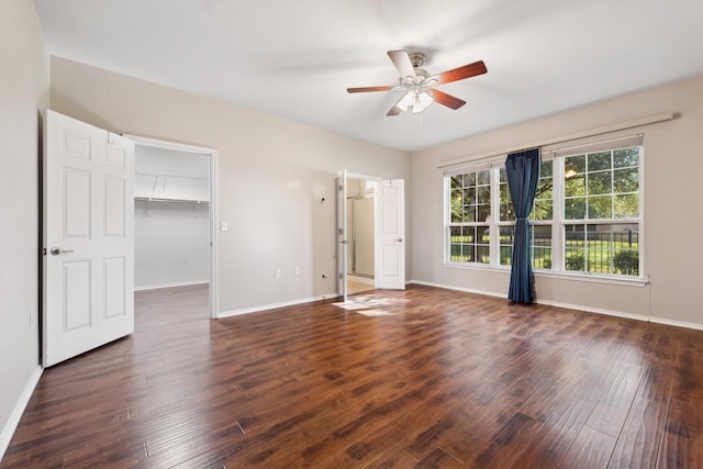 unfurnished bedroom featuring ceiling fan, a walk in closet, dark hardwood / wood-style flooring, and a closet