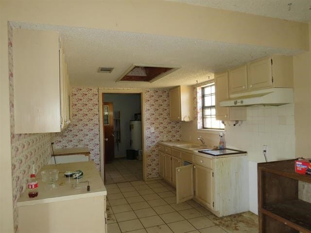 kitchen featuring a textured ceiling, cream cabinets, light tile patterned flooring, tasteful backsplash, and sink