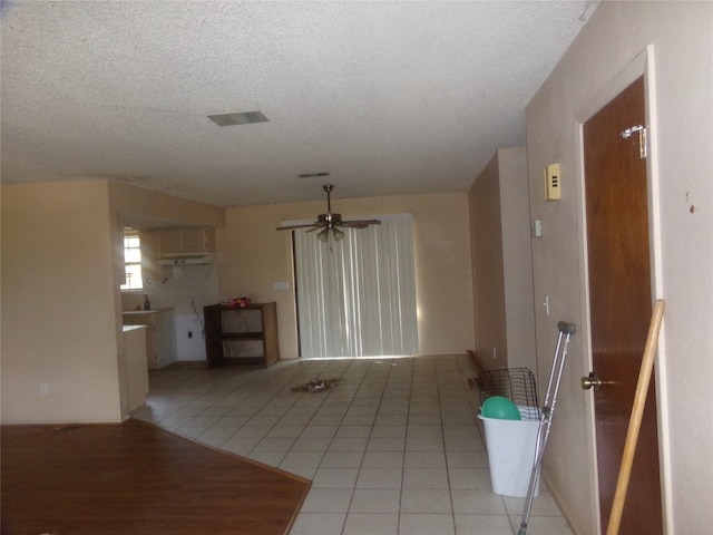 unfurnished living room with ceiling fan, light tile patterned flooring, and a textured ceiling