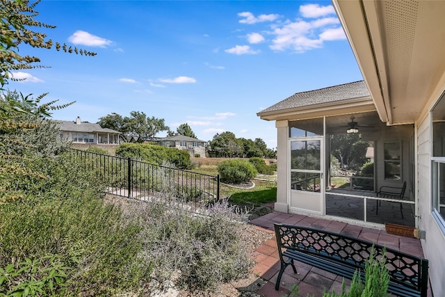 view of yard featuring ceiling fan and a sunroom