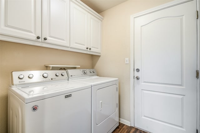 clothes washing area featuring cabinets, dark wood-type flooring, and washing machine and clothes dryer