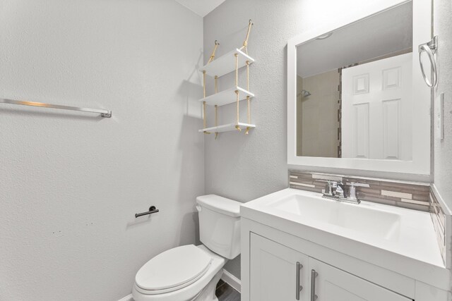 bathroom featuring backsplash, toilet, and vanity