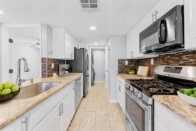 kitchen with appliances with stainless steel finishes, backsplash, sink, and white cabinetry