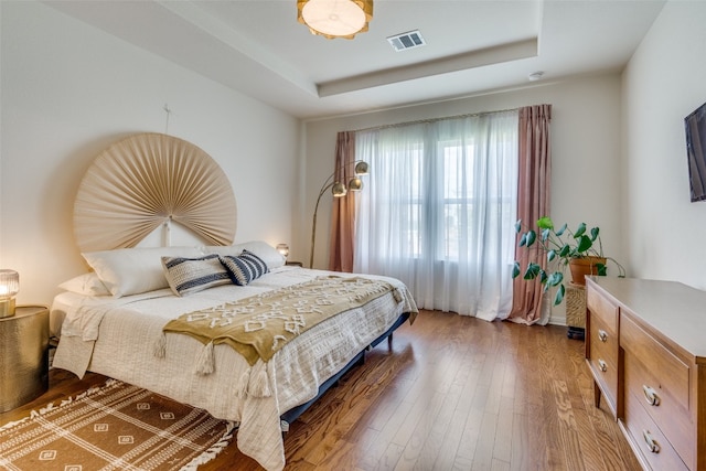 bedroom with hardwood / wood-style flooring and a tray ceiling