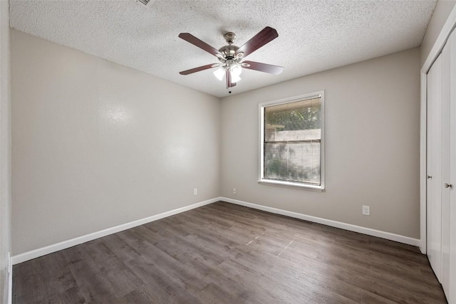 unfurnished bedroom with ceiling fan, dark hardwood / wood-style floors, a textured ceiling, and a closet