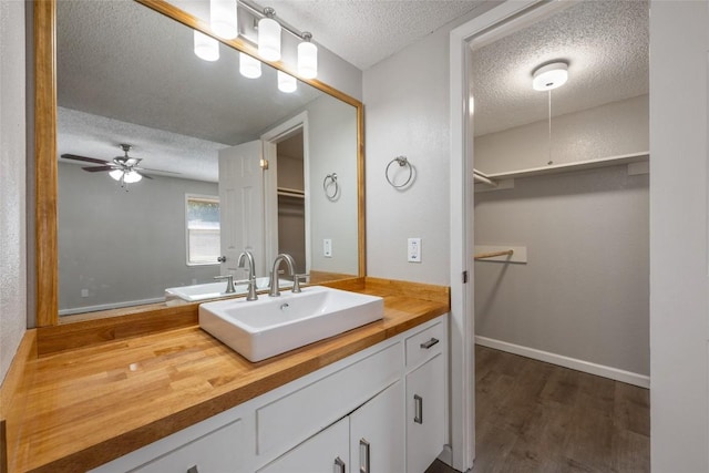 bathroom featuring hardwood / wood-style floors, ceiling fan, vanity, and a textured ceiling