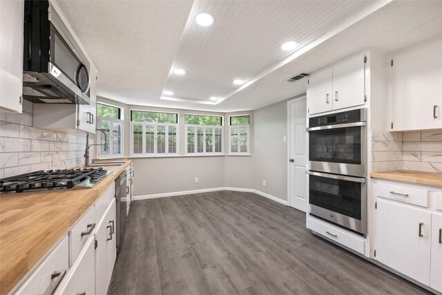 kitchen with white cabinets, dark wood-type flooring, stainless steel appliances, and decorative backsplash