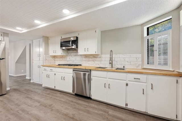 kitchen with light hardwood / wood-style flooring, sink, tasteful backsplash, appliances with stainless steel finishes, and white cabinets