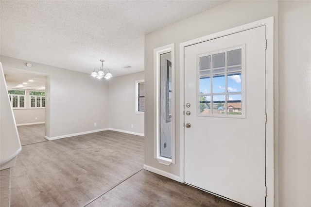 entrance foyer with a textured ceiling, hardwood / wood-style flooring, and an inviting chandelier