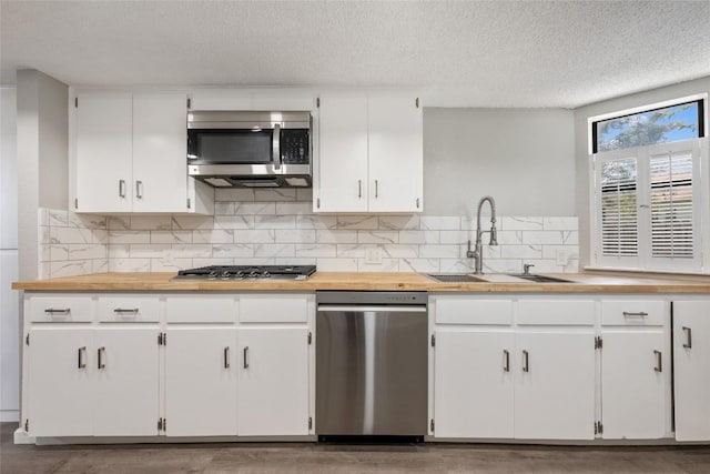 kitchen featuring appliances with stainless steel finishes, sink, backsplash, white cabinetry, and a textured ceiling