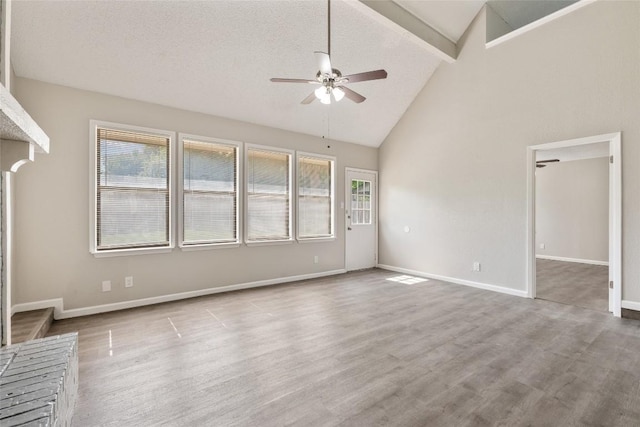 unfurnished living room with ceiling fan, light wood-type flooring, a textured ceiling, and a wealth of natural light